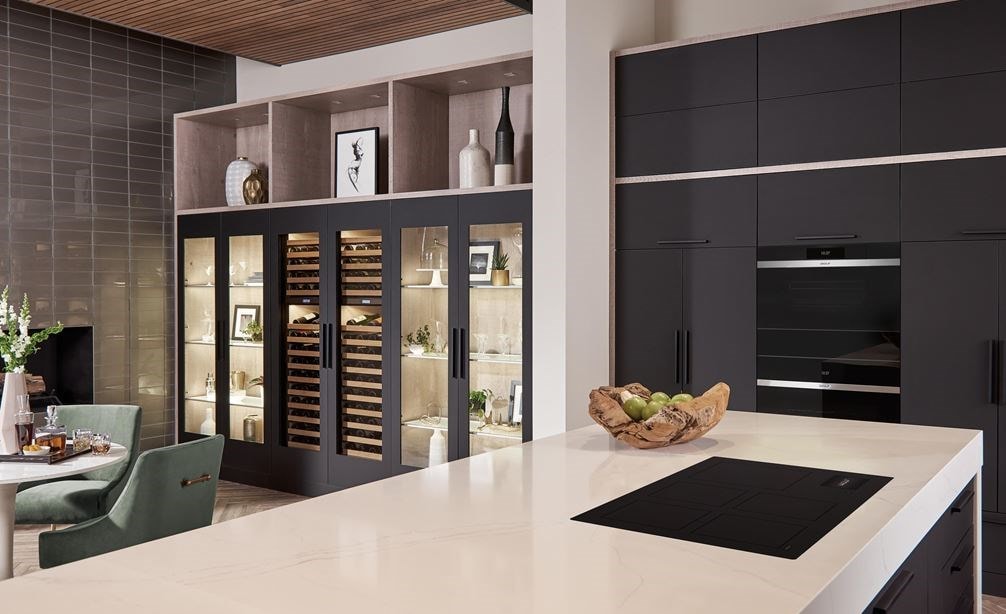 La placa de inducción contemporánea Wolf 36" (CI36560C/B) presenta un diseño conceptual de cocina abierta con una gran isla de cocina blanca y gabinetes de cocina negros.