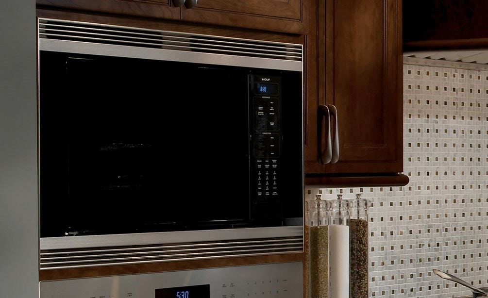 El elegante diseño negro del horno microondas de convección de 24" Wolf (MC24) agrega profundidad a esta cocina con electrodomésticos Wolf de acero inoxidable