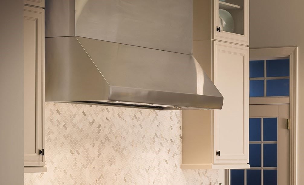 La campana extractora de pared Pro de 60" Wolf - 24" de profundidad (PW602418) es una belleza atemporal en esta elegante cocina de inspiración francesa con gabinetes blancos y mostrador de mármol
