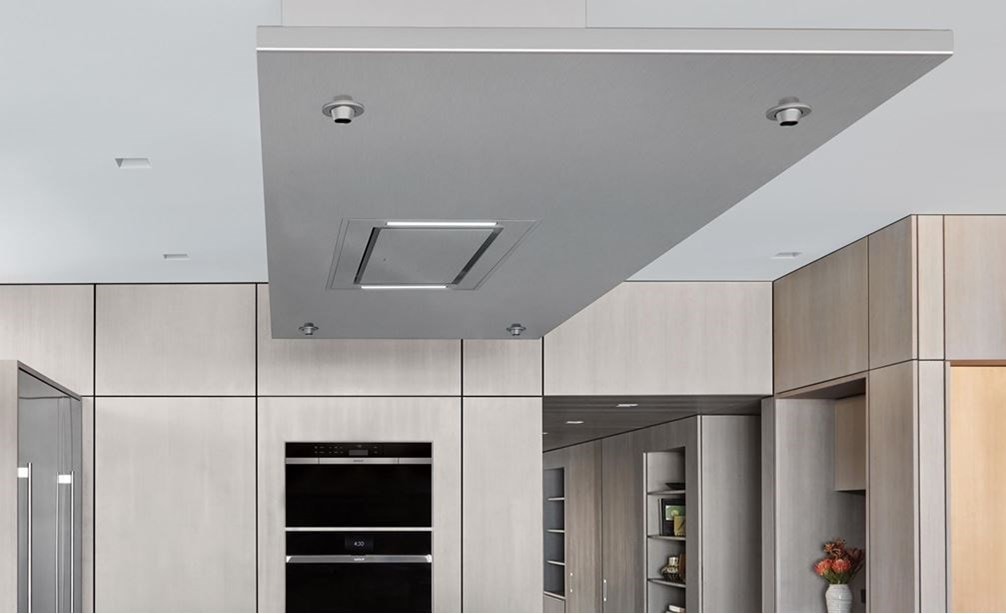 Campana extractora instalada en el techo de 36" Wolf de acero inoxidable (VC36S) exhibida combinada a la perfección sobre una gran isla de cocina en una cocina minimalista moderna