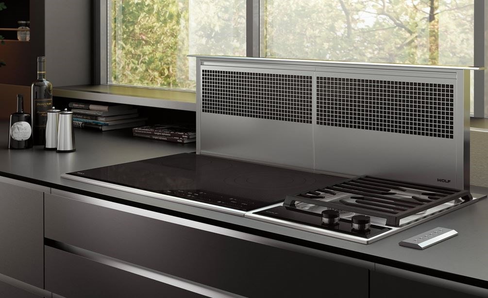 La ventilación de tiro descendente de 45" Wolf (DD45) es el toque final para este diseño de cocina ultramoderno con mostrador y gabinetes pulidos