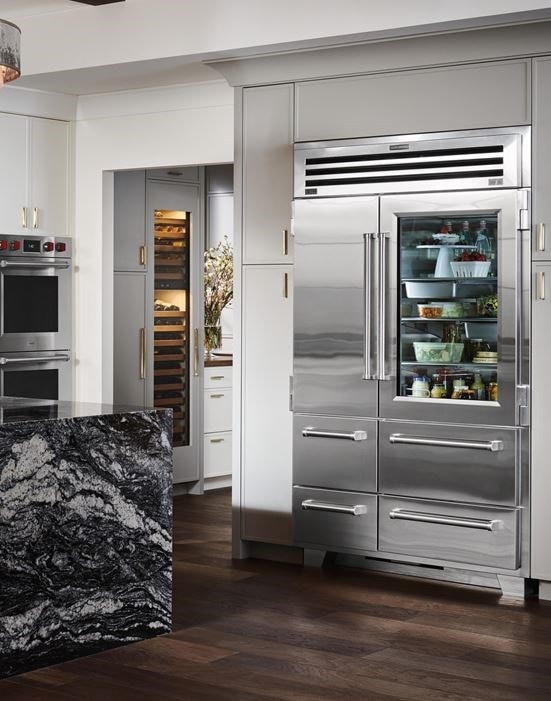 Refrigerador y congelador Sub-Zero Pro de 48" con puerta de cristal mostrado en un diseño de cocina personalizado con gran isla de cocina de mármol
