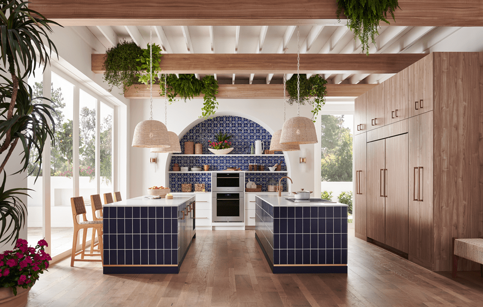 Horno de vapor con convección Wolf Transitional de la serie M de 30", exhibido en una cocina mediterránea con doble isla, salpicadero de azulejos azules personalizados y techo con vigas de madera expuestas