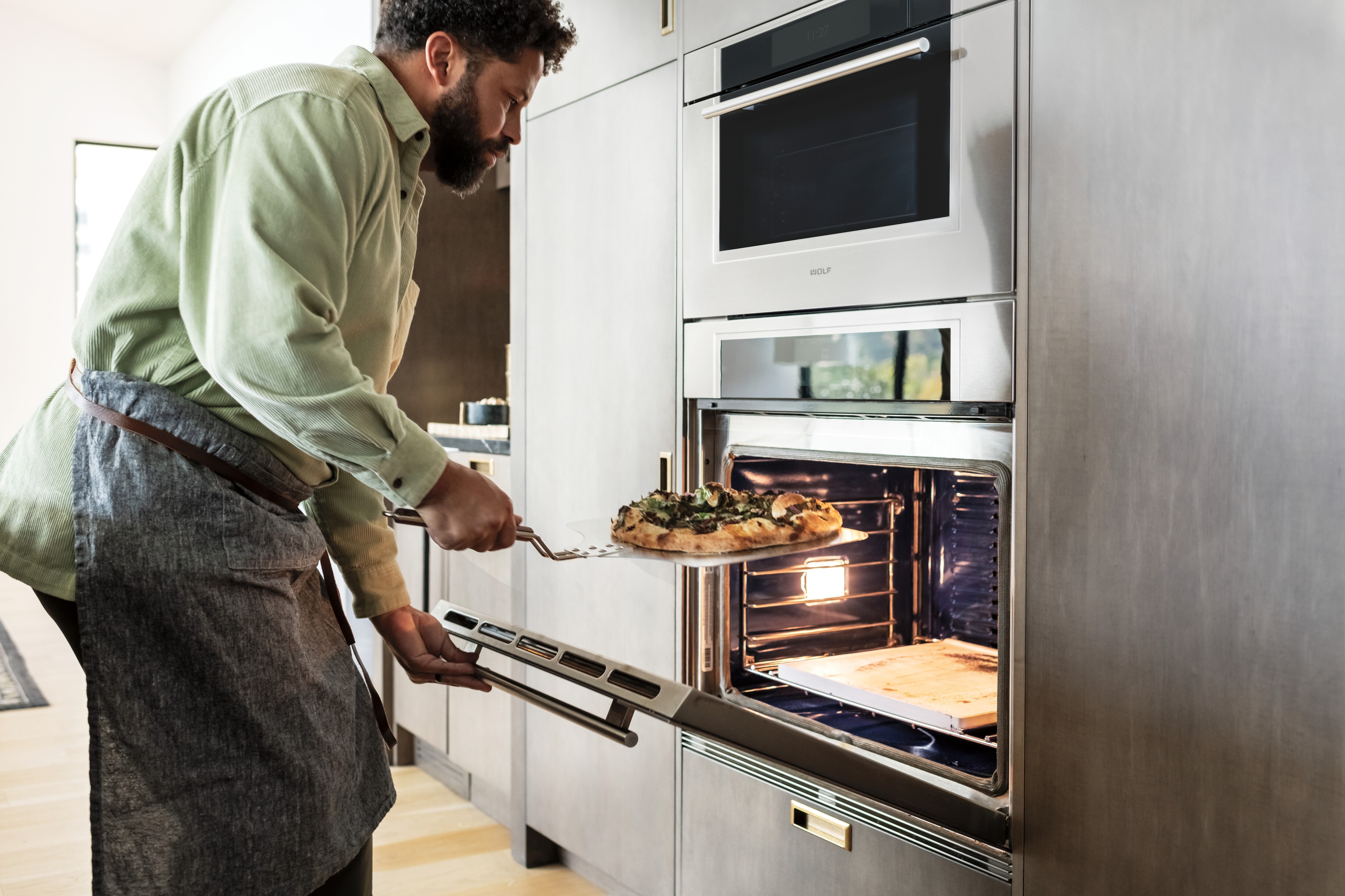 El horno de vapor con convección y el horno individual transicional Wolf de la serie M de 30" mostrados a ras en los gabinetes de cocina personalizados