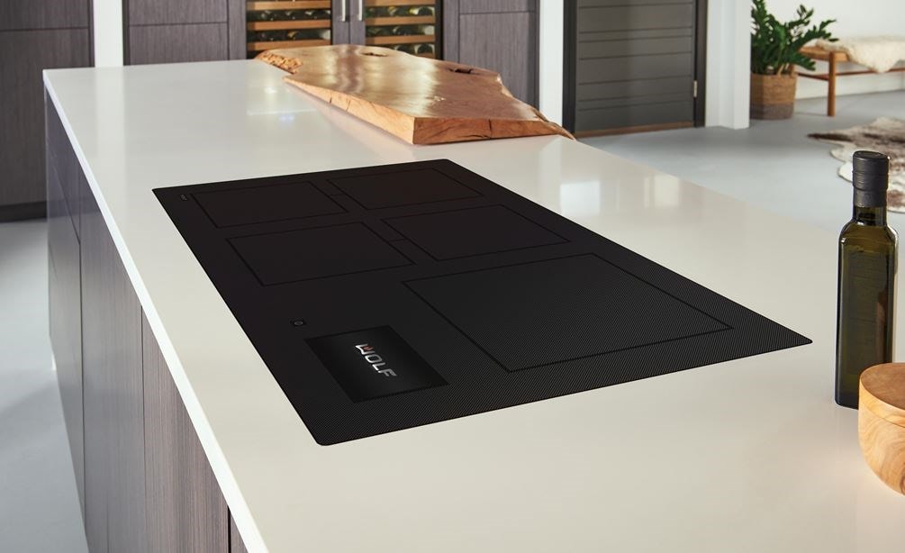 La placa de inducción contemporánea de 36" Wolf (CI36560C/B) presenta un diseño de cocina moderno, que se combina a la perfección con los mostradores blancos con gabinetes de tonos cálidos de madera.