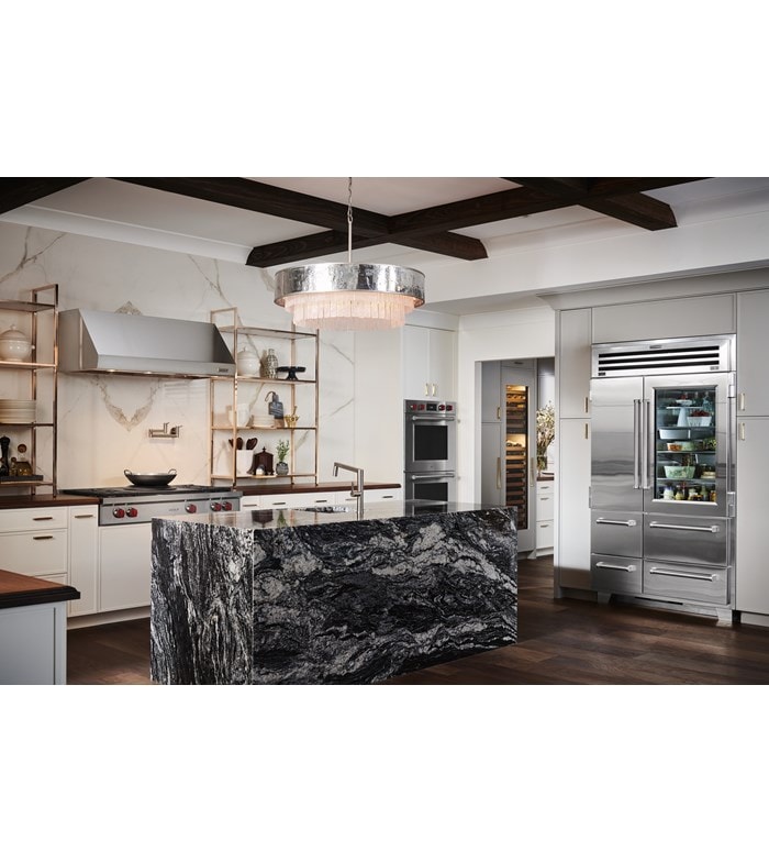 Refrigerador y congelador Sub-Zero Pro de 48" con puerta de cristal mostrado en un diseño de cocina personalizado con gran isla de cocina de mármol