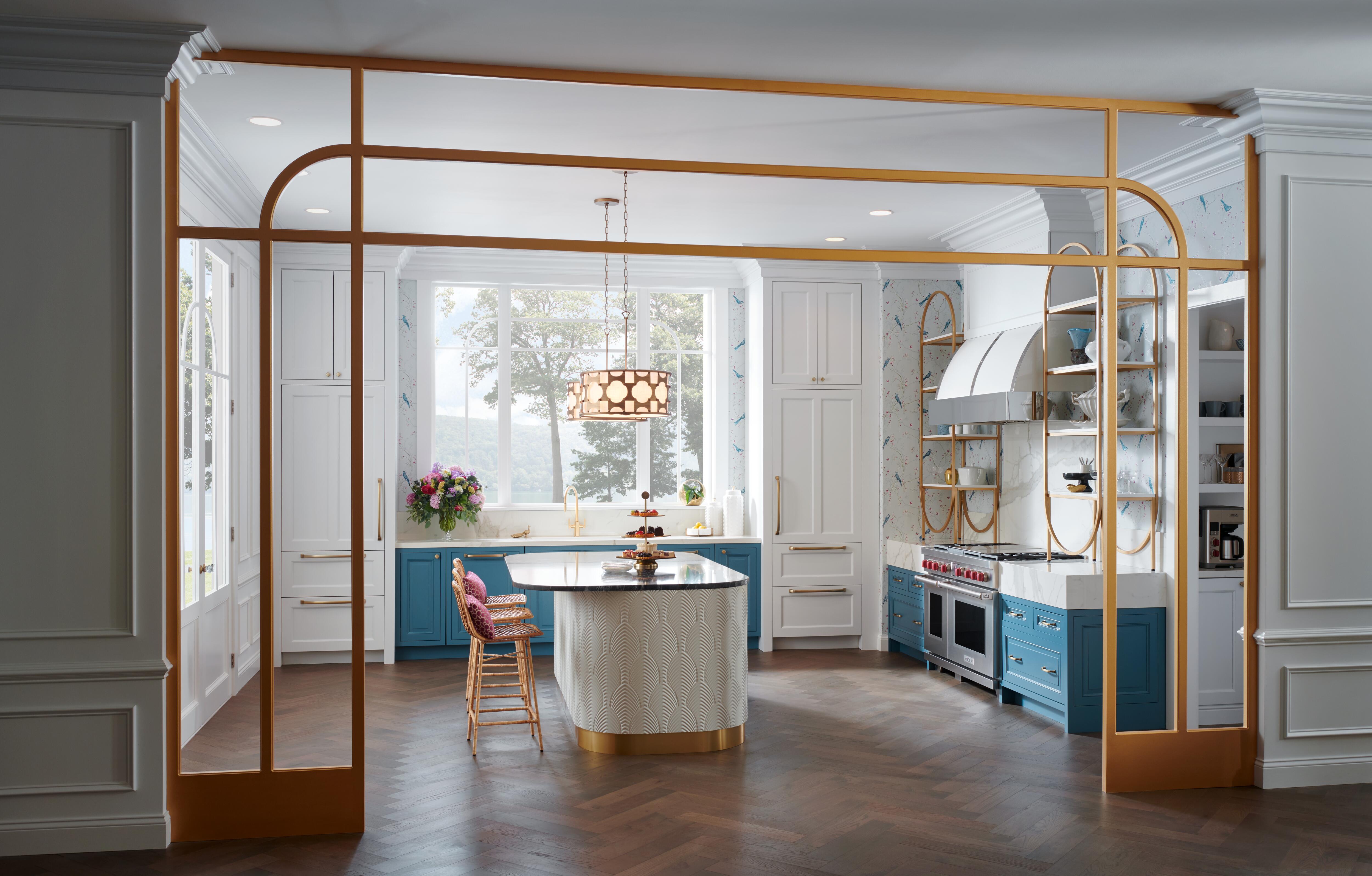 Los electrodomésticos Wolf se exhiben en un diseño de cocina personalizado con estantes abiertos, accesorios dorados y mostradores de mármol blanco