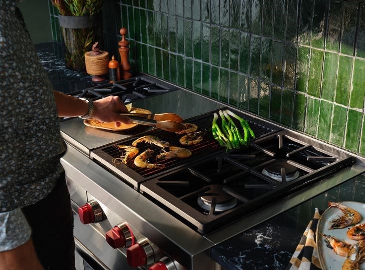 A man cooking a few pieces of food on his Wolf Range.