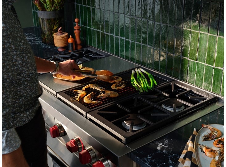A man cooking a few pieces of food on his Wolf Range.