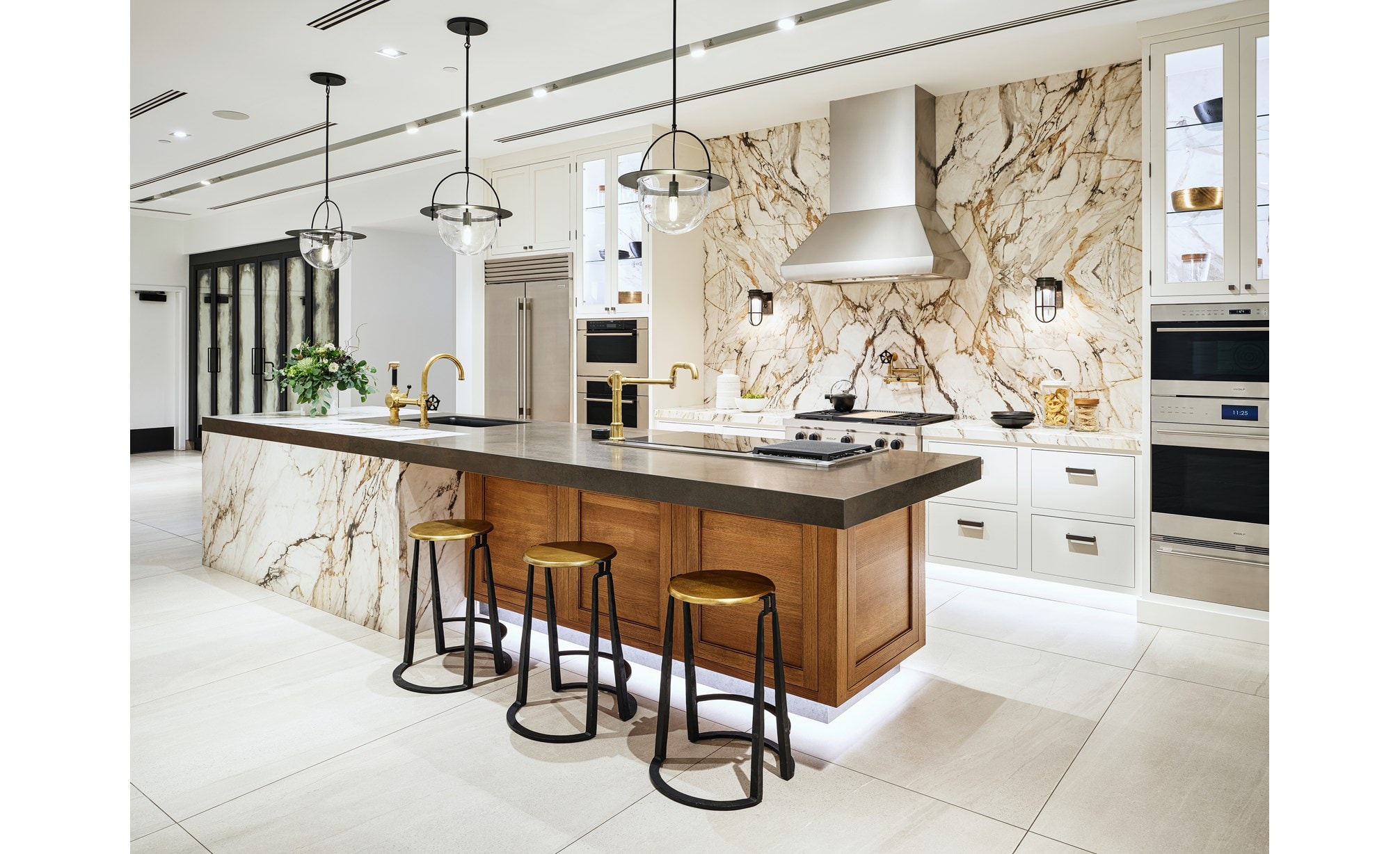 A white kitchen vignette with a black countertop featuring an array of Sub-Zero, Wolf, and Cove appliances.