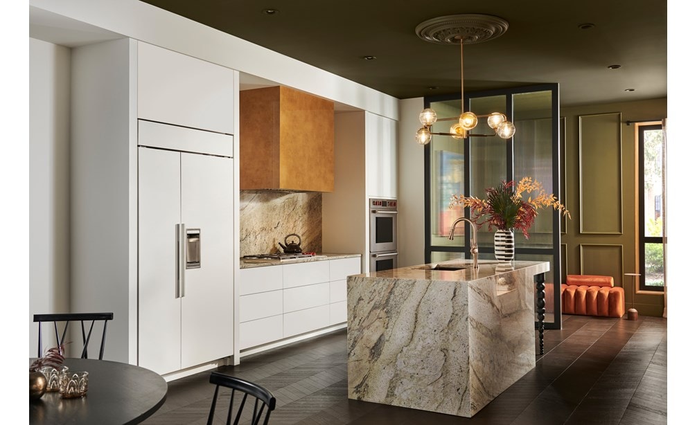 Refrigerador Sub-Zero de la serie Classic de 42" Side-by-side integrable que se combina a la perfección en los gabinetes blancos de esta cocina moderna y audaz, con una isla de granito y salpicadero a juego