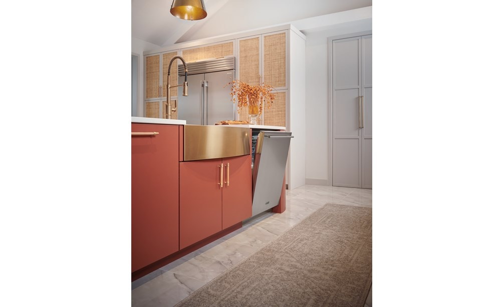24 inch Stainless Steel Dishwasher by Cove Dishwashers shown with stainless steel door ajar next to a copper color farmhouse sink with red kitchen cabinets