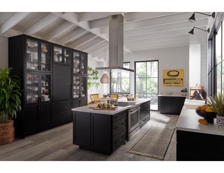 Estufa de inducción de 36” y 34” Wolf (IR36550/S/T) exhibida en un gran espacio de cocina abierto y luminoso con suelos de madera cálida y vigas de techo blancas superpuestas.