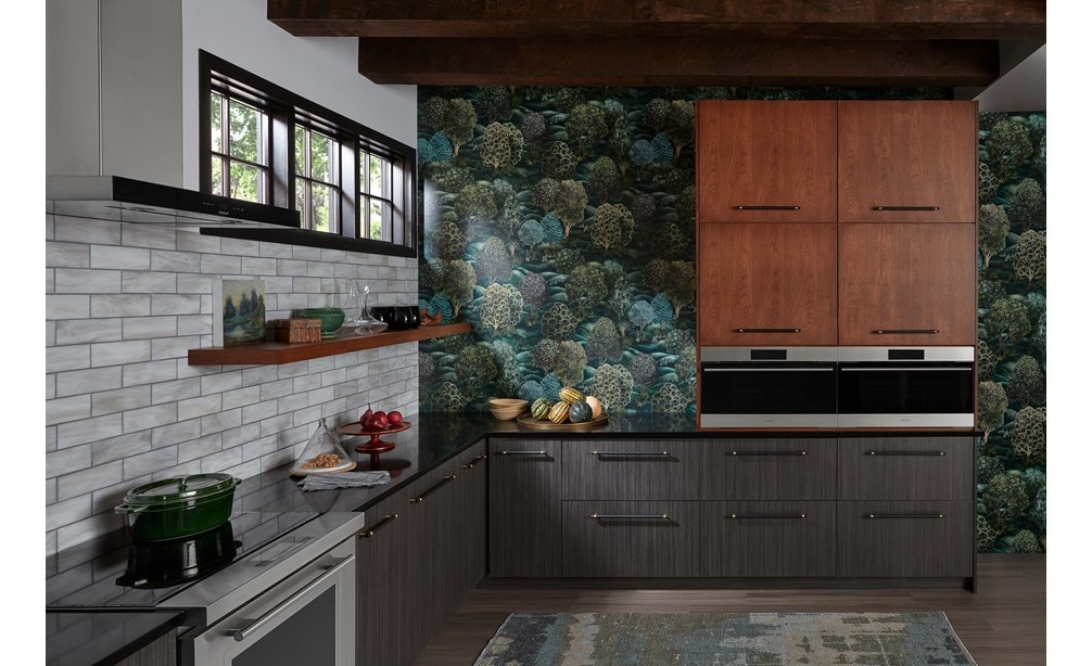 Two built-in Wolf Appliances in a colorful kitchen with green wallpaper, brown cabinetry, and a Wolf Ventiliation System.