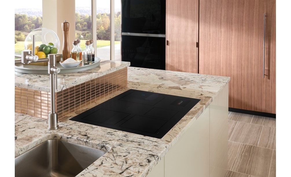 Placa de inducción contemporánea de 30" Wolf que se muestra al ras montada en el mostrador de la cocina de mármol blanco.