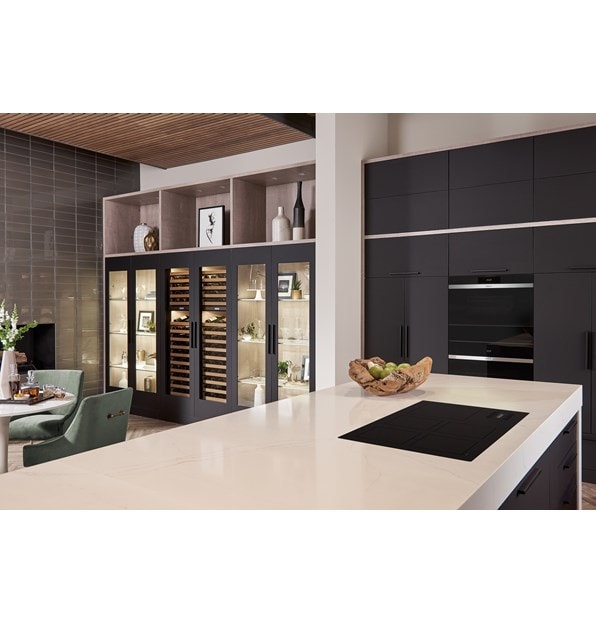 La placa de inducción contemporánea Wolf 36" (CI36560C/B) presenta un diseño conceptual de cocina abierta con una gran isla de cocina blanca y gabinetes de cocina negros.