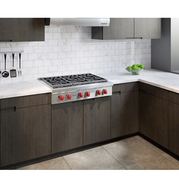 La estufa de 6 quemadores sellados de 36" Wolf (SRT366) brilla en este entorno clásico de cocina junto a gabinetes de panel plano y paredes de ladrillo blanco