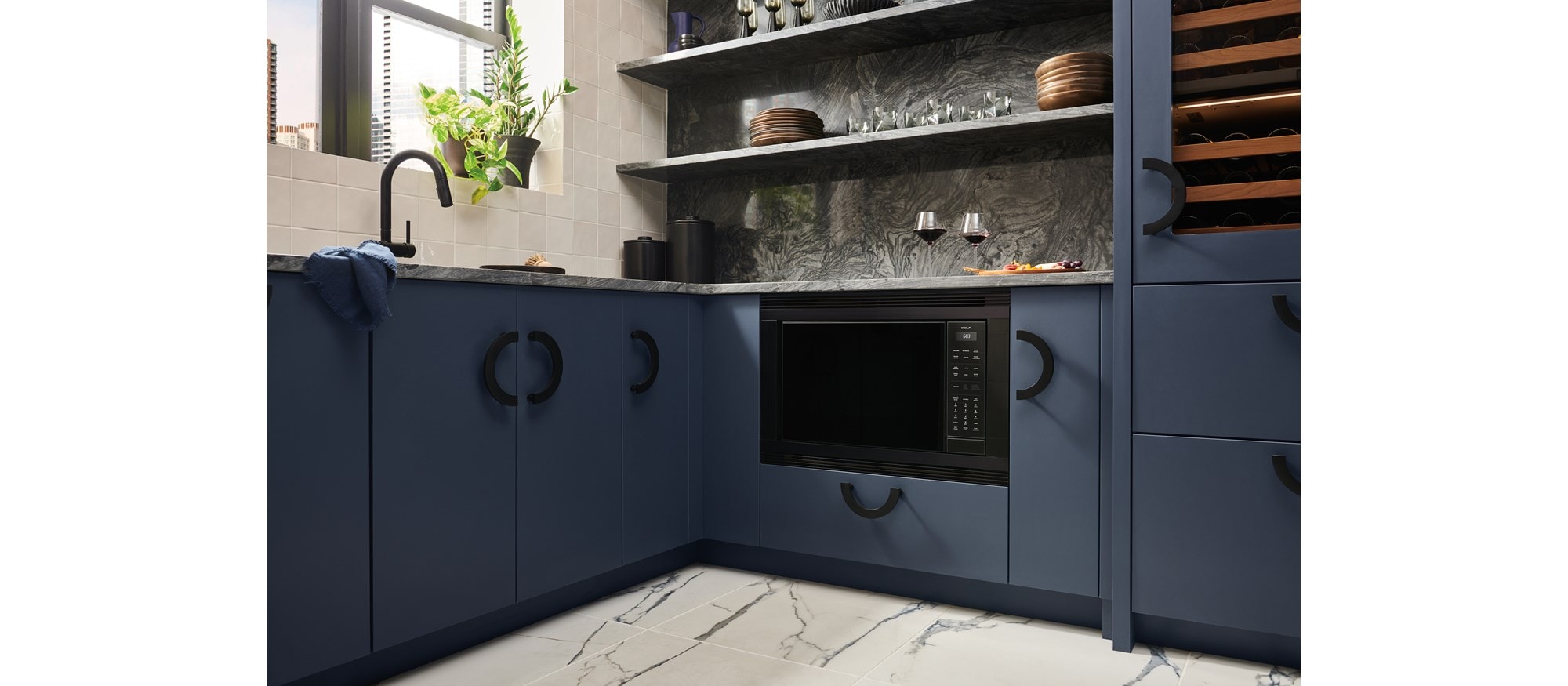 Wolf Standard Swing Microwave flushed with the cabinetry of a luxury, blue-colored kitchen.