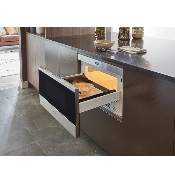 El cajón microondas transicional de 24" Wolf (MD24TE/S) que se muestra aquí con una instalación a ras en una pared de gabinetes lisos ultramodernos