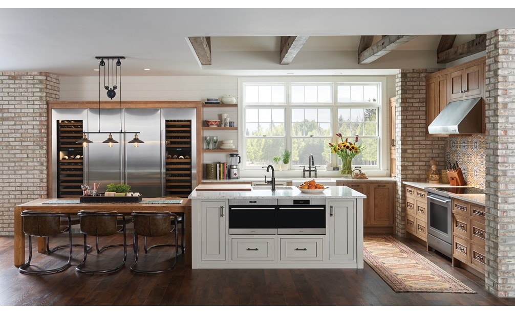 Horno microondas con puerta abatible transicional de 24" Wolf de la serie E (MDD24TE/S/TH) exhibido con una instalación al ras en una gran isla de cocina de granito personalizada