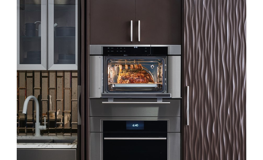 Horno de vapor con convección transicional de la serie M de 30" Wolf (CSO30TM/S/TH) exhibido en una elegante disposición de gabinetes de cocina con acabado pulido y calido