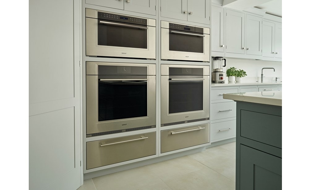 El horno de vapor con convección transicional de la serie M de 30" Wolf (CSO30TM/S/TH) en la despensa personalizada de madera oscura ofrece elegancia visual y comestible