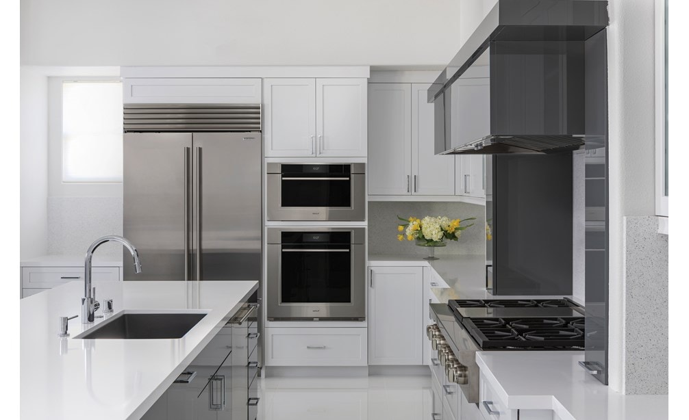 Horno de vapor con convección transicional de la serie M de 30" Wolf (CSO3050TM/S/T) en una cocina poco iluminada con suelos y mostradores blancos brillantes