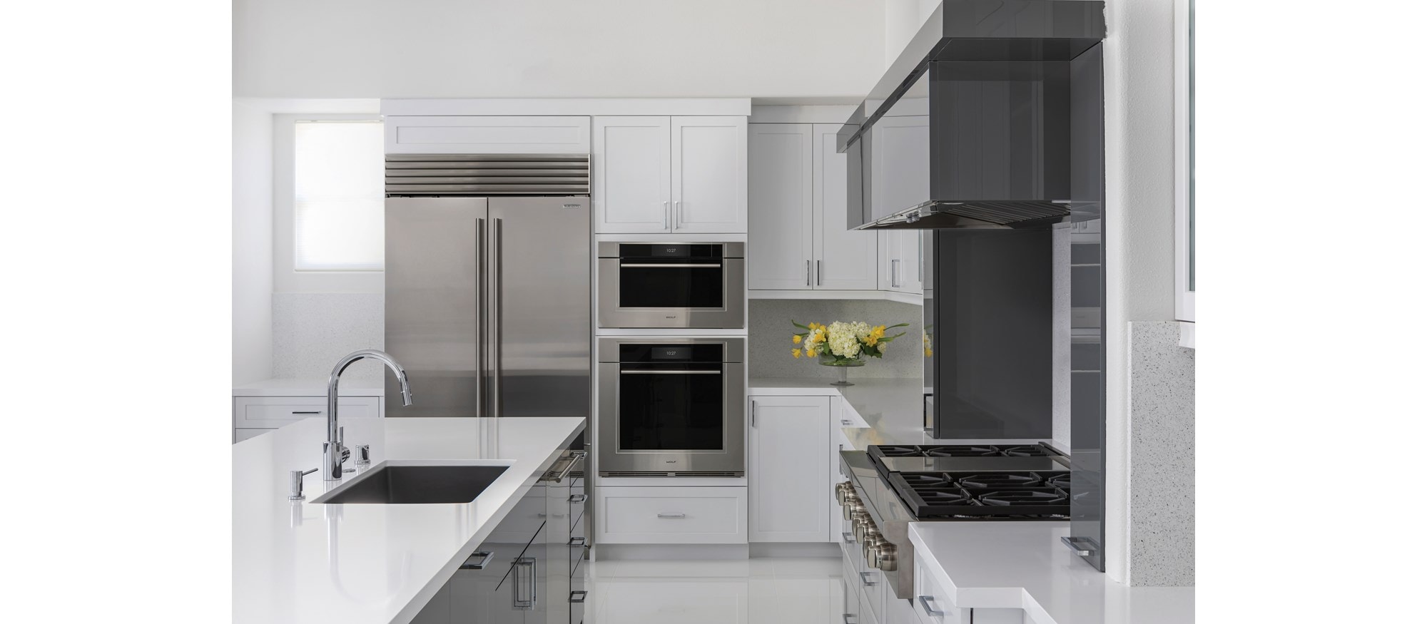 Horno de vapor con convección transicional de la serie M de 30" Wolf (CSO3050TM/S/T) en una cocina poco iluminada con suelos y mostradores blancos brillantes