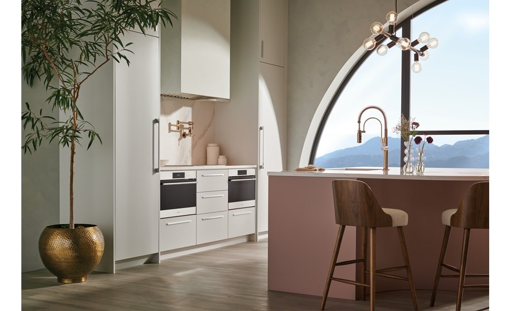 Horno de vapor con convección transicional de la serie E de 24" Wolf con tubería (CSOP2450TE/S/P) instalado en una cocina de gabinetes personalizados de color negro brillante con vistas a montañas