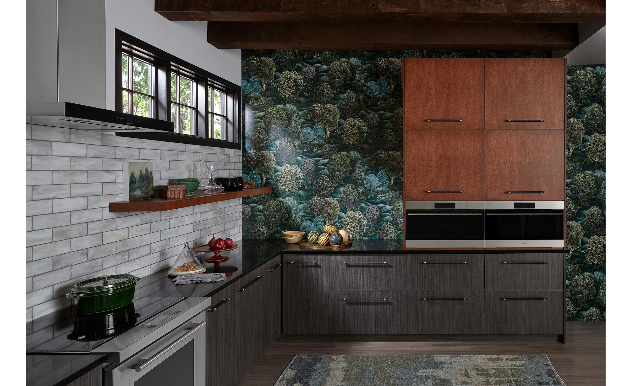 Two built-in Wolf Appliances in a colorful kitchen with green wallpaper, brown cabinetry, and a Wolf Ventiliation System.