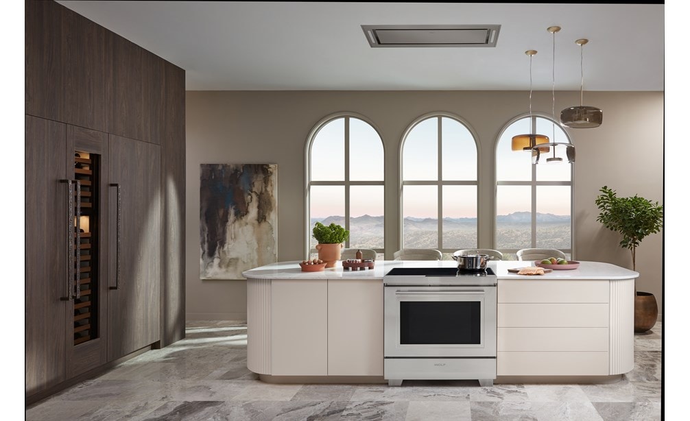 Wolf 30" Induction Range shown centered in front of arch windows in sleek custom kitchen island with pendant light above. 