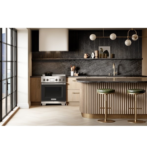 Wolf 30 Inch Professional Induction Range featuring black accent oven door and knobs paired with a Wolf Professional Hood Liner are displayed in a sleek high rise kitchen design.