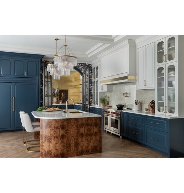 Wolf Professional Induction Range with stainless accent oven door and iconic red knobs displayed in an open kitchen design featuring Sub-Zero Classic Refrigerator and Freezer hidden within custom blue cabinetry .