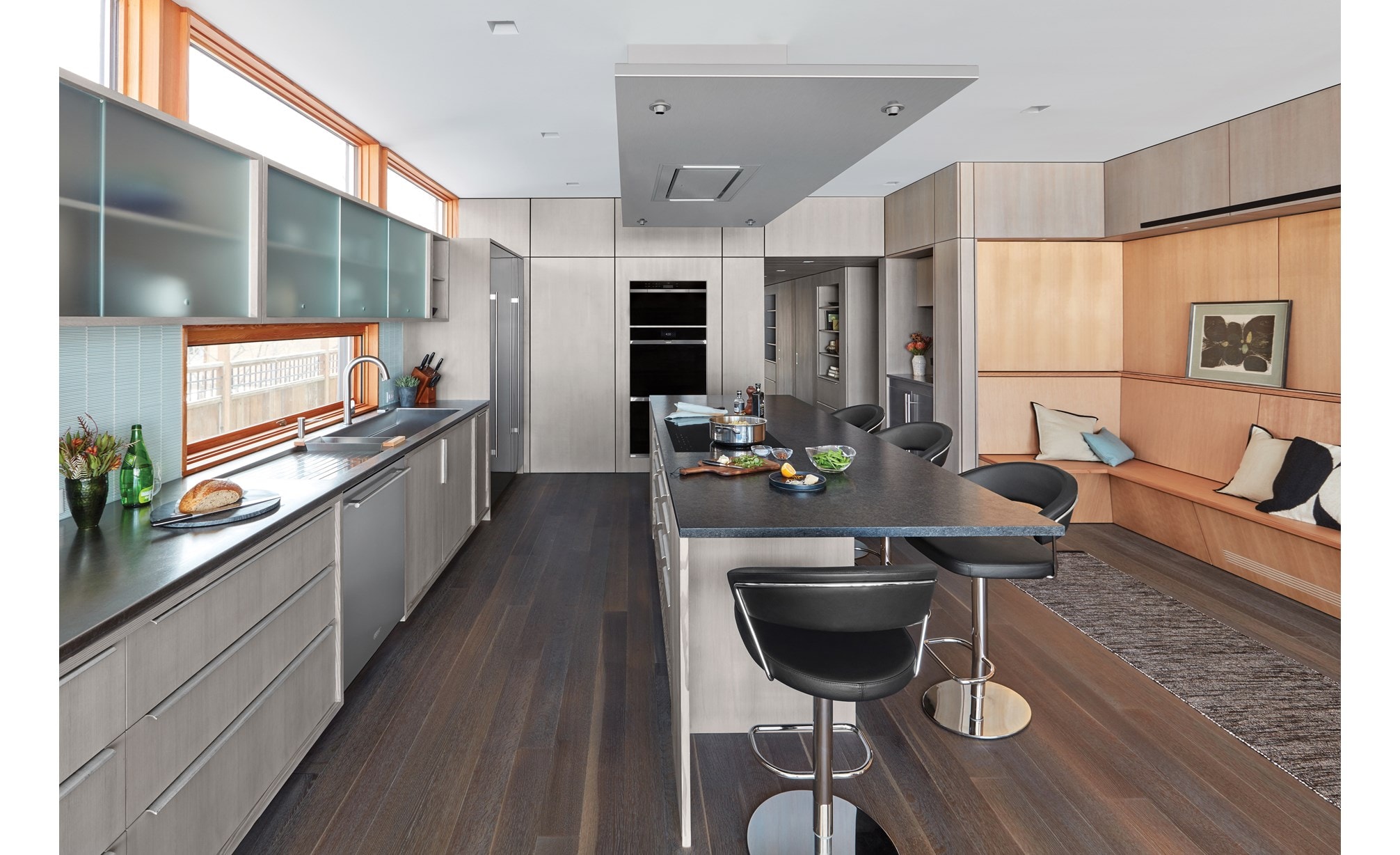 Campana extractora instalada en el techo de 36" Wolf de acero inoxidable (VC36S) exhibida combinada a la perfección sobre una gran isla de cocina en una cocina minimalista moderna