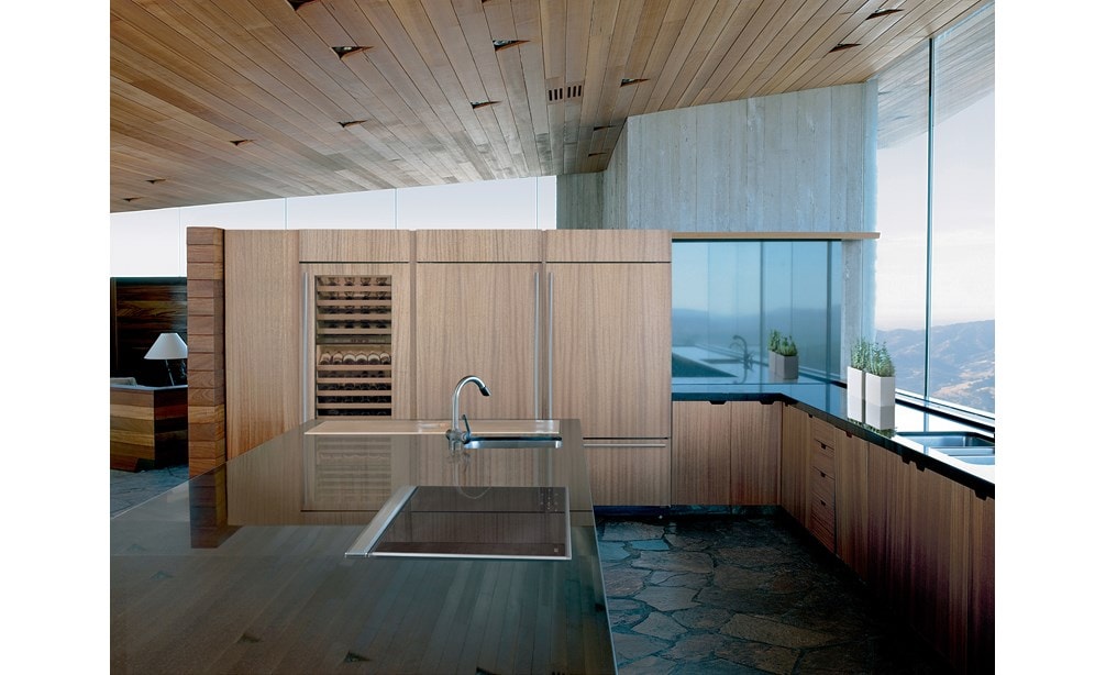 La ventilación de tiro descendente de 30" Wolf (DD30) exhibida con placa de inducción transicional de 30" Wolf (CI304T/S) en una decoración de madera natural mínima