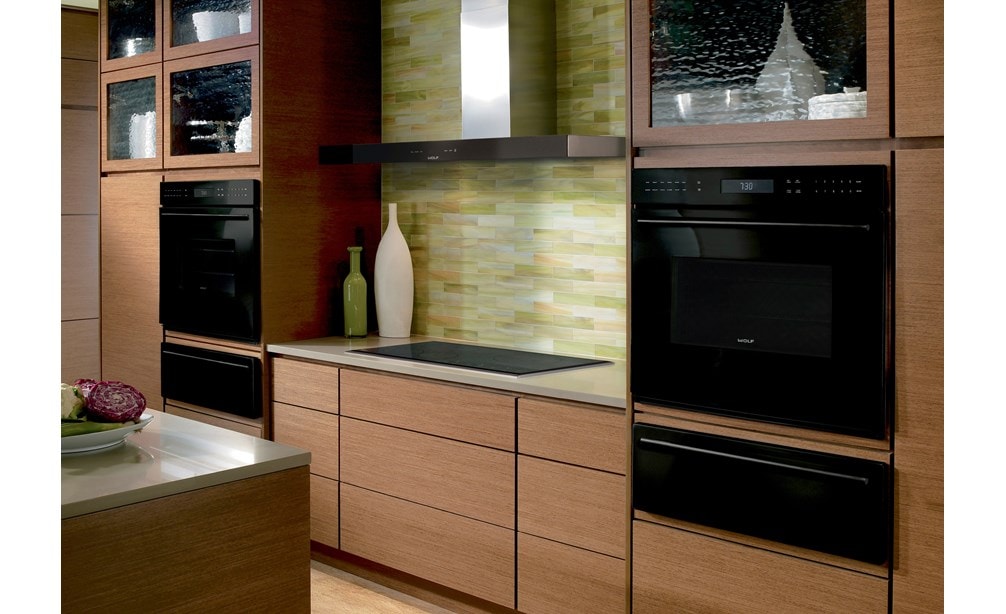 La campana extractora de pared de 45" Wolf en negro (VW45B) exhibida con una variedad de electrodomésticos Wolf en la cálida cocina contemporánea