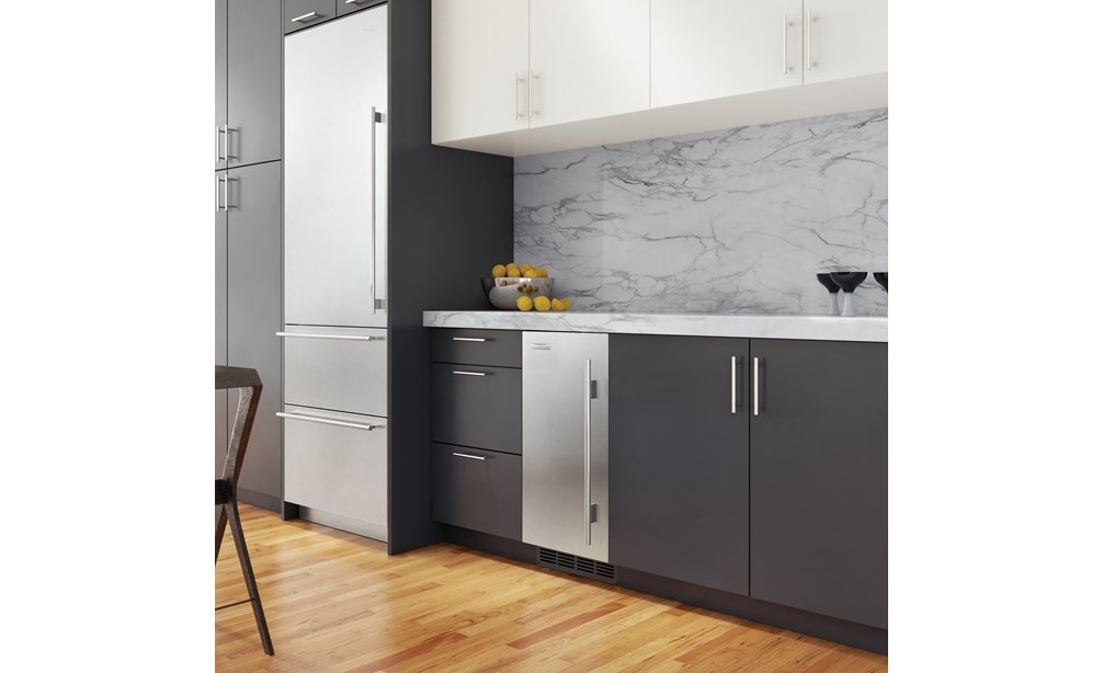 La máquina para hacer hielo de 15” Sub-Zero compatible con paneles (UC-15I) exhibida combinada a la perfección en armarios lisos de tonos oscuros para un diseño elegante.