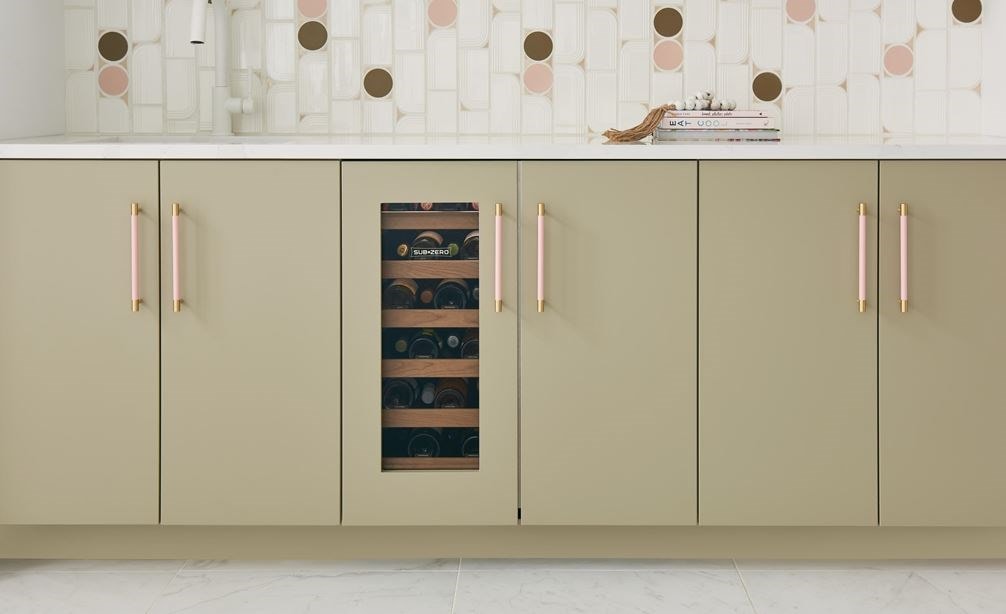 Frontal view of closed Sub-Zero 15" Designer Undercounter Beverage Center with Solid Door - Panel Ready (DEU1550B) shown in a row of tan custom cabinets