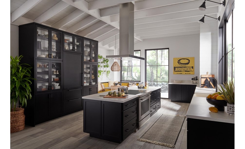 Estufa de inducción de 36” y 34” Wolf (IR36550/S/T) exhibida en un gran espacio de cocina abierto y luminoso con suelos de madera cálida y vigas de techo blancas superpuestas.