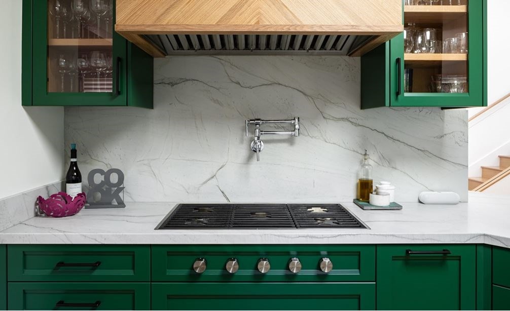 Placa de cocción de gas contemporánea de 36 pulgadas Wolf presentada en una cocina pequeña y elegante con gabinetes verdes y salpicadero de mármol.