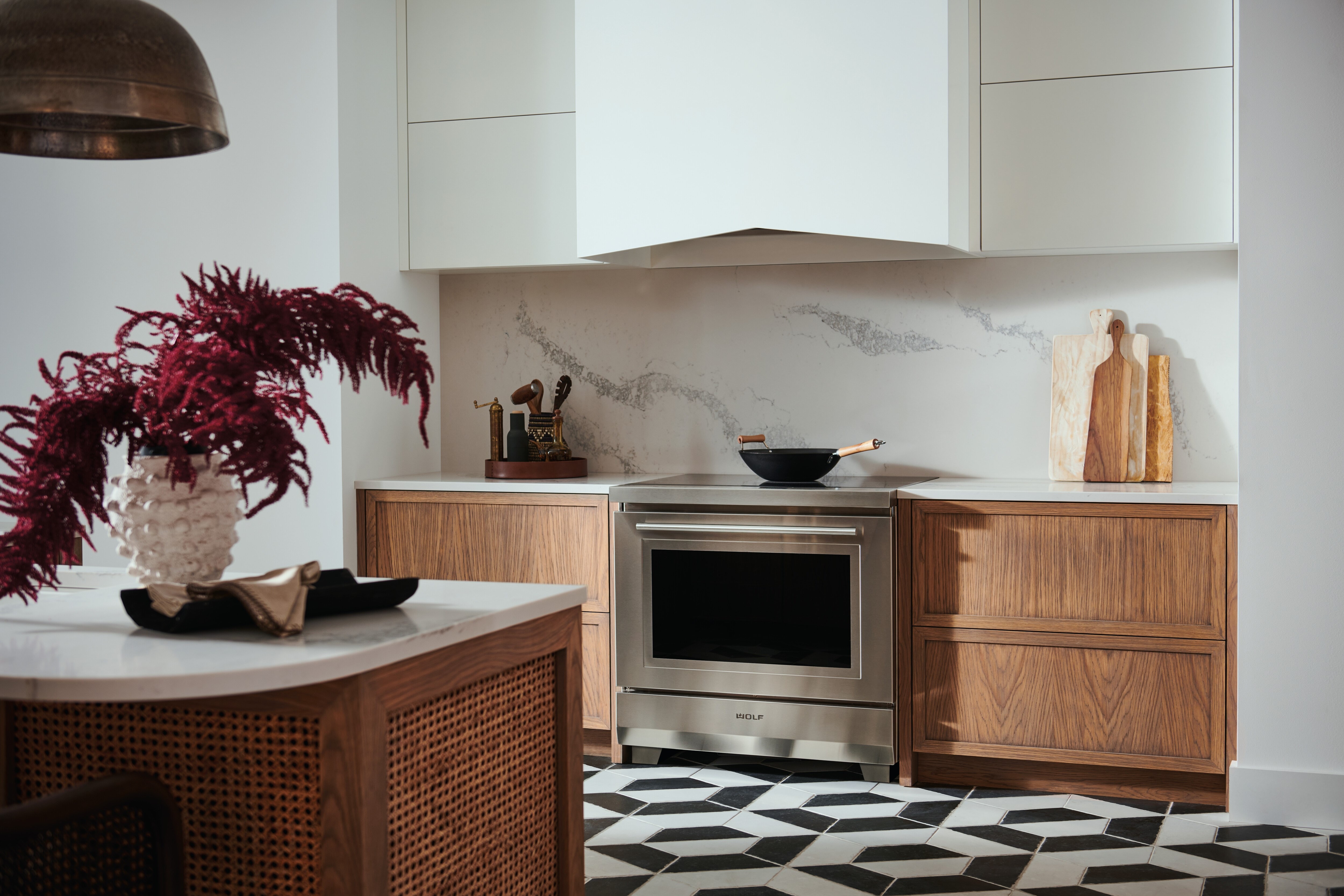 Estufa de inducción transicional de 36” Wolf (IR36550/S/T) exhibida con revestimiento de campana Pro de 40” Wolf (PL402212)