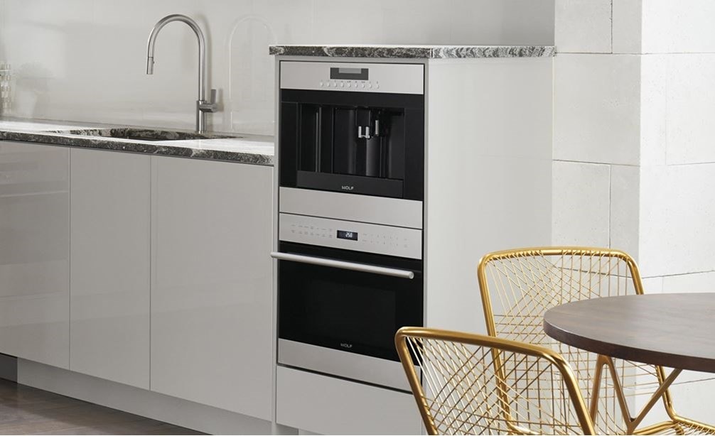 El sistema para café de 24" Wolf de acero inoxidable (EC24/S) exhibido en una elegante cocina contemporánea con gabinetes lisos sin manijas
