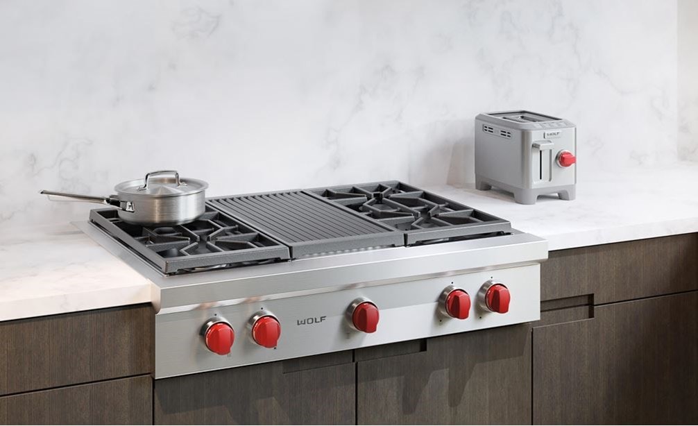 La estufa y asadora infrarroja de 4 quemadores sellados de 36" Wolf (SRT364C) exhibidos en una integración elegante en un entorno de cocina tradicional.