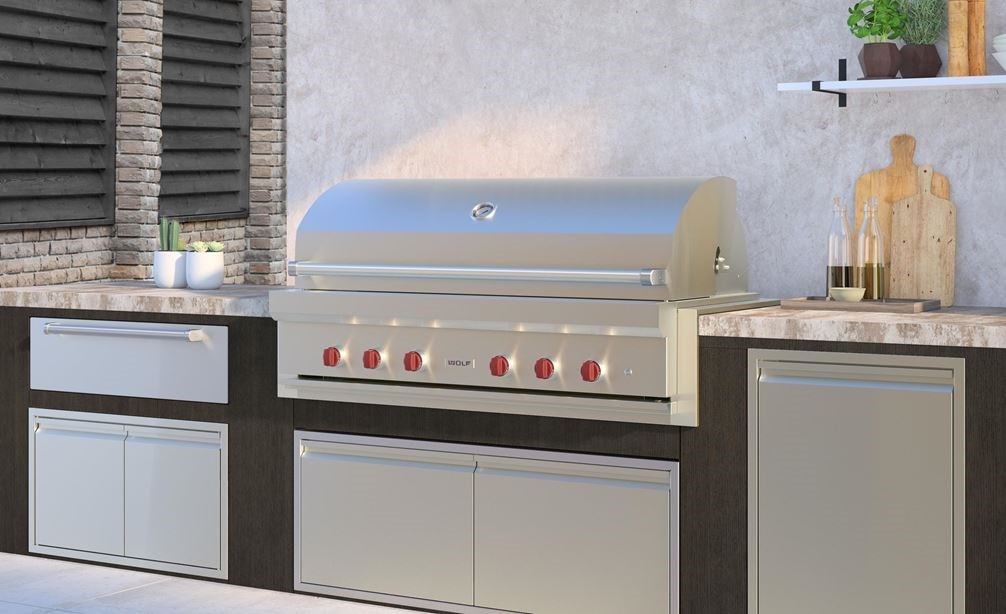 La parrilla de gas para exteriores de 54" Wolf (OG54) exhibida en una cocina de lujo para exteriores con electrodomésticos de cocina para exteriores de calidad profesional.
