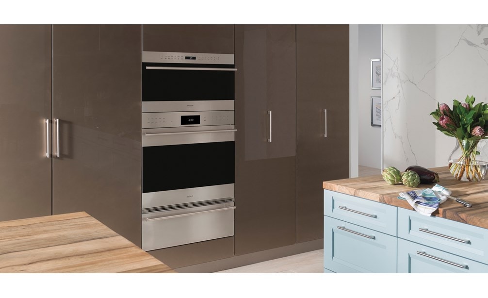 El horno microondas con puerta abatible transicional de 30" Wolf de la serie E (MDD30TE/S/TH) exhibido con una instalación al ras en gabinetes lisos de piso a techo