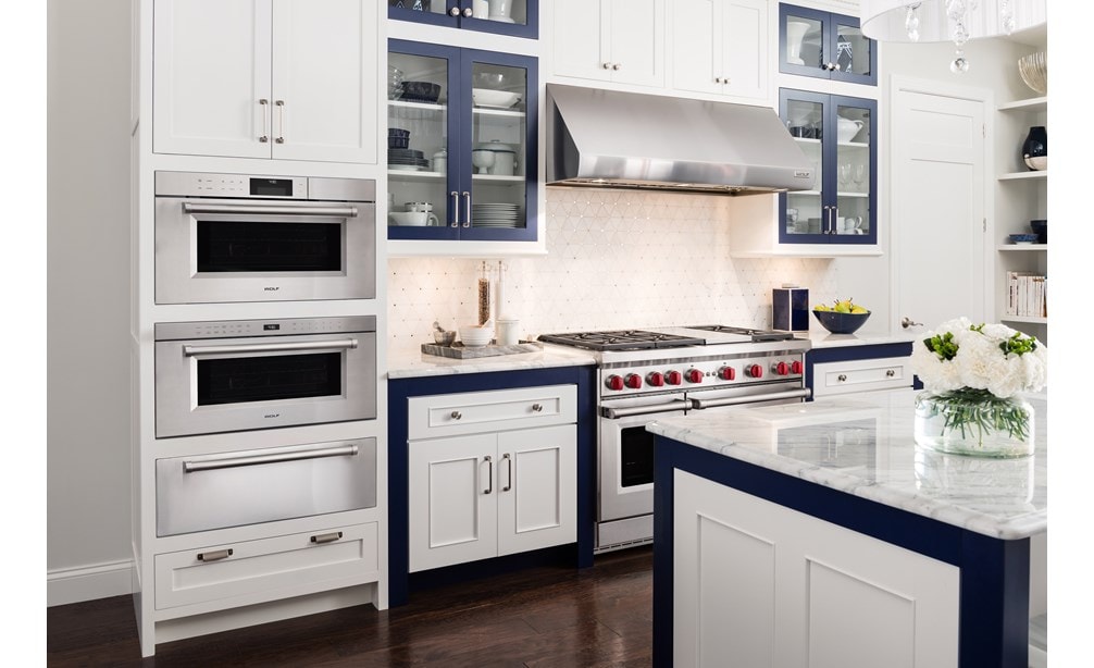 Horno microondas con puerta abatible profesional de 30" Wolf de la serie M (MDD30PM/S/PH) en una cocina elegante con gabinetes blancos y exhibidores de mármol