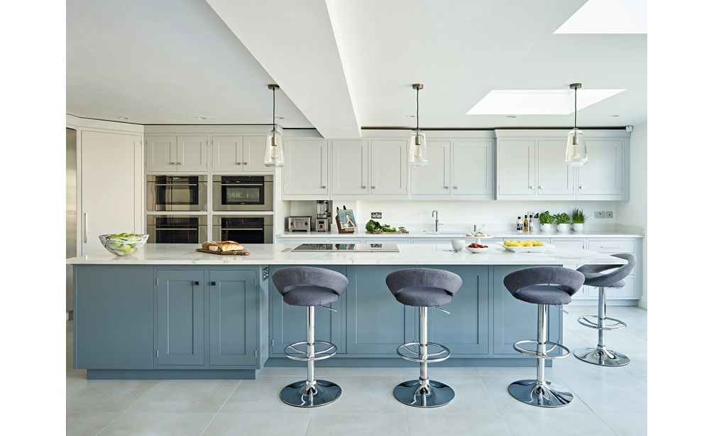 Horno microondas con puerta abatible transicional de 30" Wolf de la serie M (MDD30TM/S/TH) colocado en diseño blanco clásico con una enorme isla para comer en la cocina