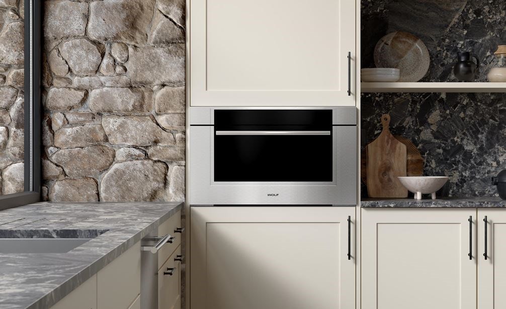 A close-up of the Wolf Transitional Speed Oven inside a brick kitchen with white-colored cabinets