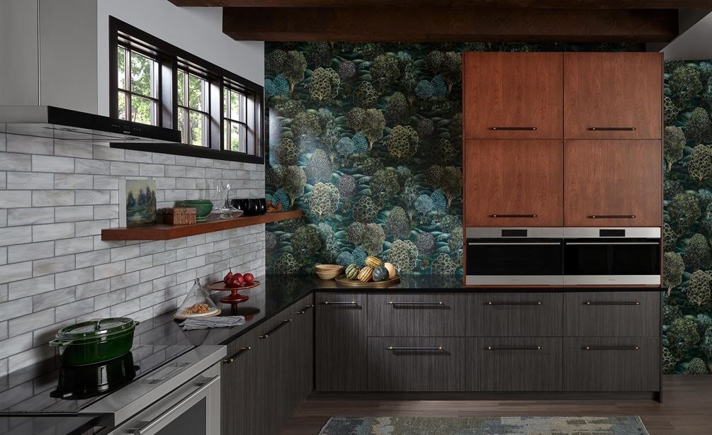 Two built-in Wolf Appliances in a colorful kitchen with green wallpaper, brown cabinetry, and a Wolf Ventiliation System.