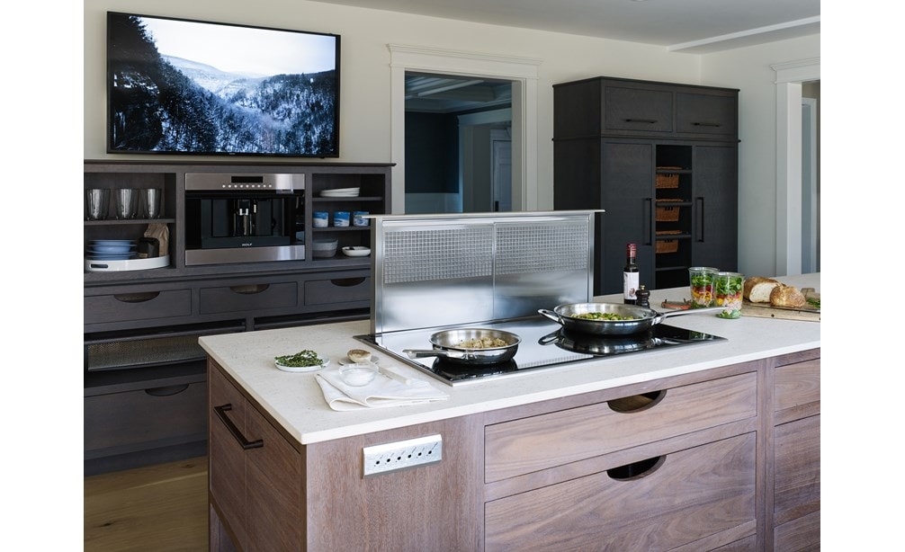 Ventilación de tiro descendente de 36" Wolf (DD36) exhibida con placa de inducción transicional de 36" Wolf (CI365T/S) en isla de cocina con acabado de madera natural